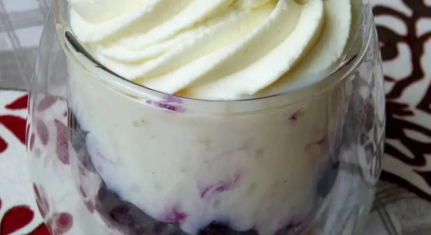 Délicieuse mousse chocolat blanc aérienne, parsemée de fruits rouges, servie dans un verre.