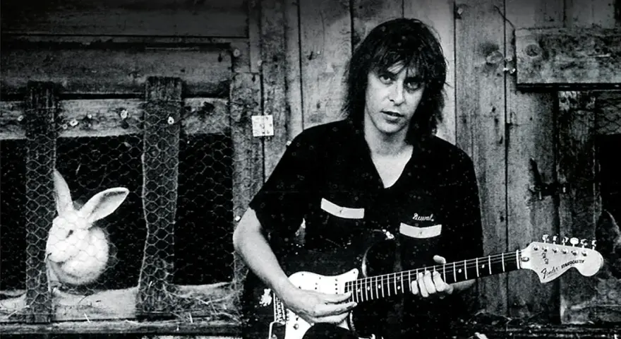 Ein Mann mit Gitarre, im Hintergrund ein Hase im Käfig. Ein Bild, das an den **titel von Rio Reiser** erinnert.