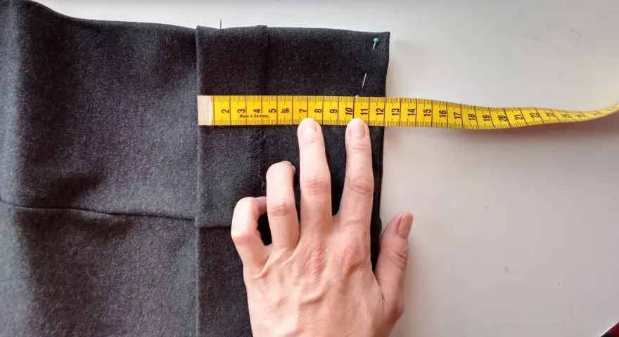 Mierzysz, jak skrócić spodnie ręcznie. Miarka krawiecka pokazuje ok. 11 cm.