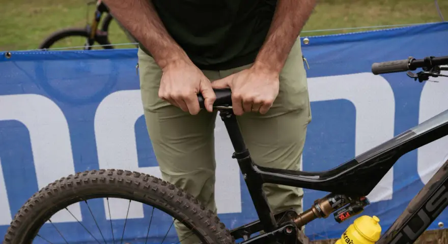 A rider adjusts their seat on a full-suspension bike, ready for an enduro mountain biking adventure.