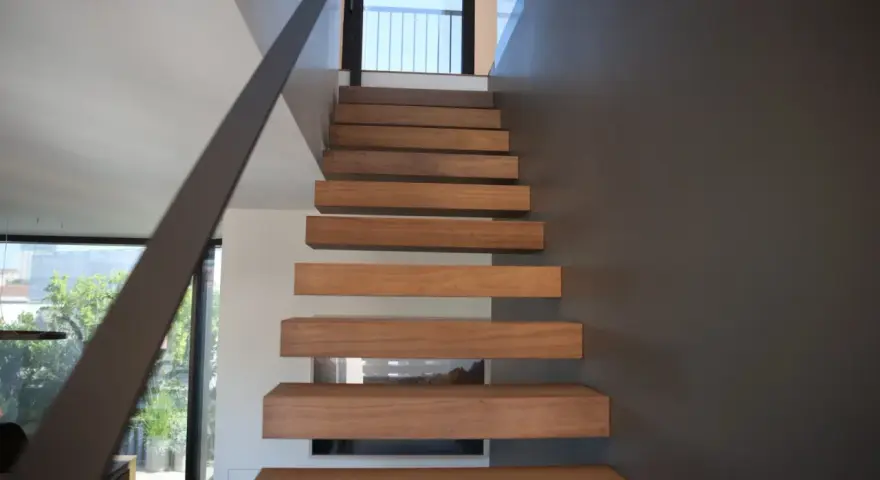 Moderna scala interna con gradini in legno sospesi, un'idea di design minimalista e funzionale.