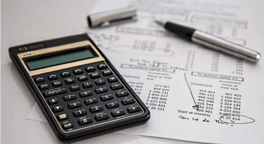 Calculadora y bolígrafo sobre un balance de situación. El balance de situación muestra cifras de inversión y valor al cierre del año.