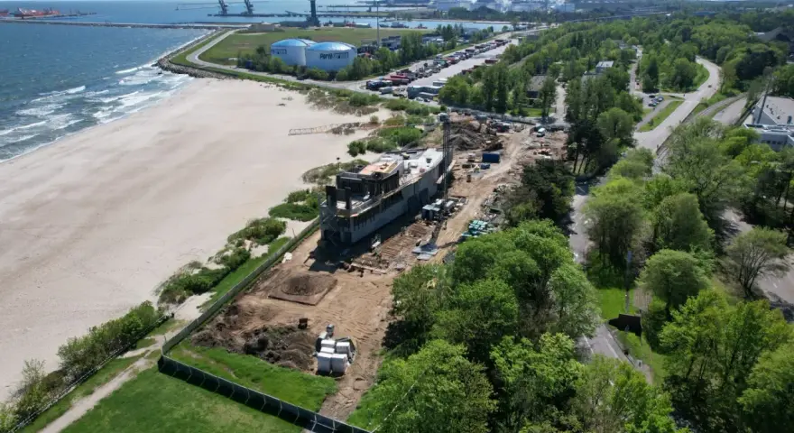 Budowa obiektu przy plaży, w tle port i morze. Idealne miejsce na parking z widokiem na morze.