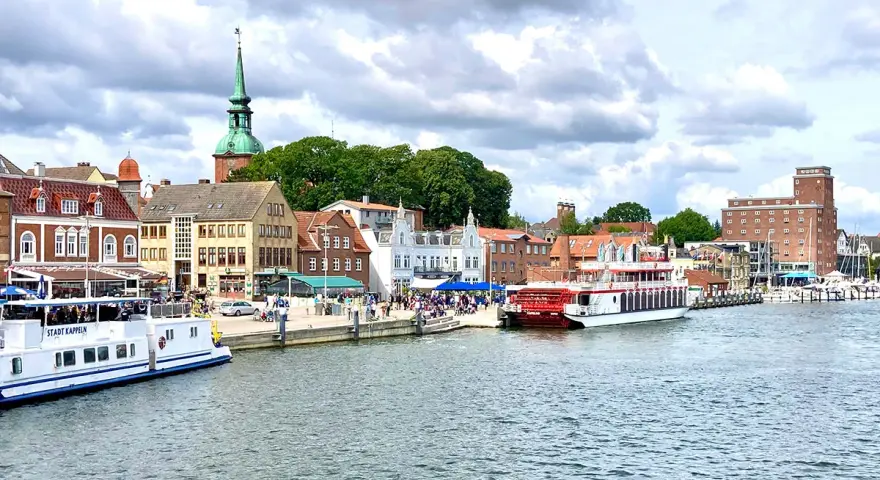 Hafen von Kappeln mit Schiffen und historischen Gebäuden. Entdecken Sie die Kappeln Geheimtipps für Ihren nächsten Urlaub.