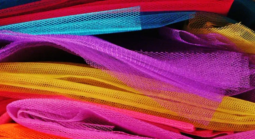 Un tas de **tulle** aux couleurs vives : orange, rose, jaune, violet, bleu et rouge.