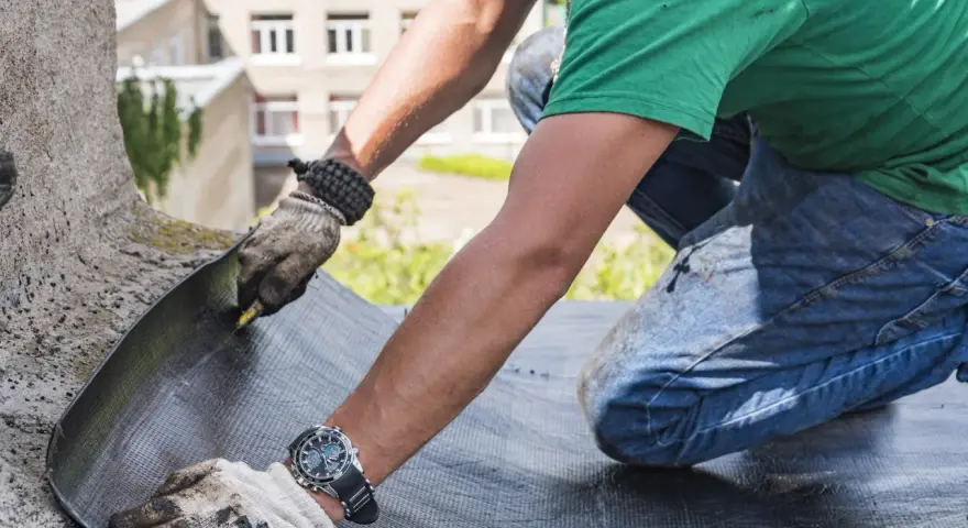 Trabajador realiza impermeabilización de terrazas, cortando material para asegurar la protección contra el agua.