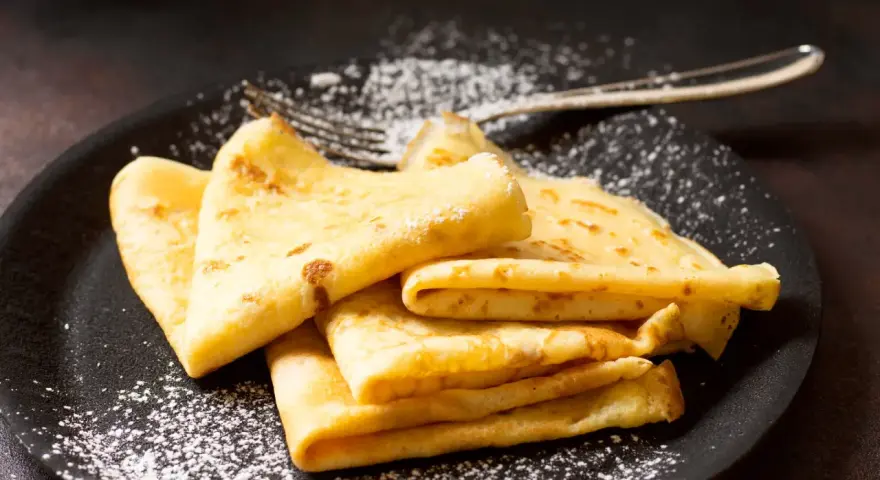 Délicieuses crêpes dorées, saupoudrées de sucre glace, prêtes à être dégustées. La pâte à crêpe Thermomix, un jeu d'enfant !