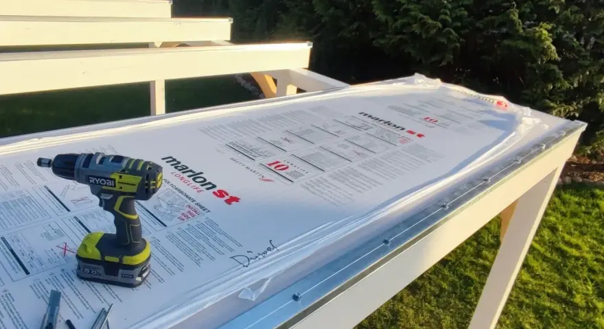 Werkzeug liegt bereit, um Hohlkammerplatten zu schneiden. Ein Akkuschrauber, Cutter und Schrauben auf der neuen Überdachung.