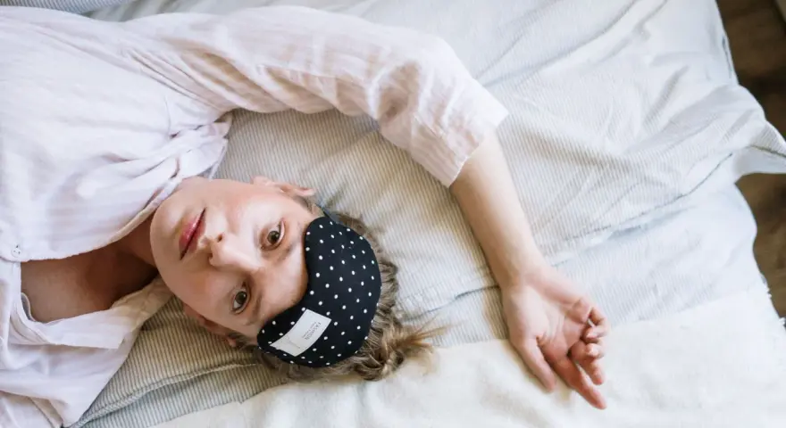 Donna con mascherina per dormire, cerca rimedi per l'insonnia da stress.
