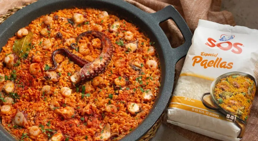 Paella de marisco con un tentáculo de pulpo visible, gambas y trozos de calamar. Al lado, un paquete de arroz SOS Especial Paellas.