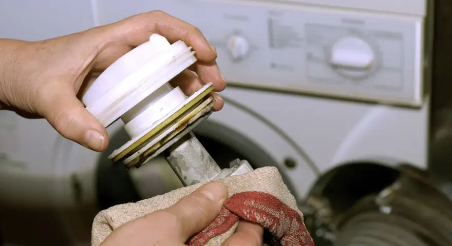 Hände reinigen das Flusensieb einer Bosch Waschmaschine. Regelmäßige Pflege sorgt für einwandfreie Funktion.