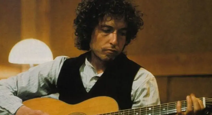 Bob Dylan gra na gitarze, tworząc swoje legendarne utwory.