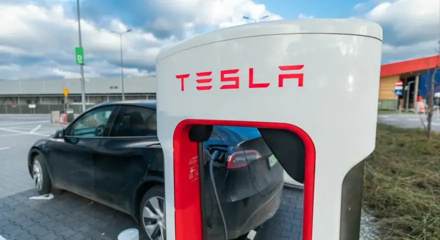 Czarna Tesla podłączona do ładowarki Supercharger.