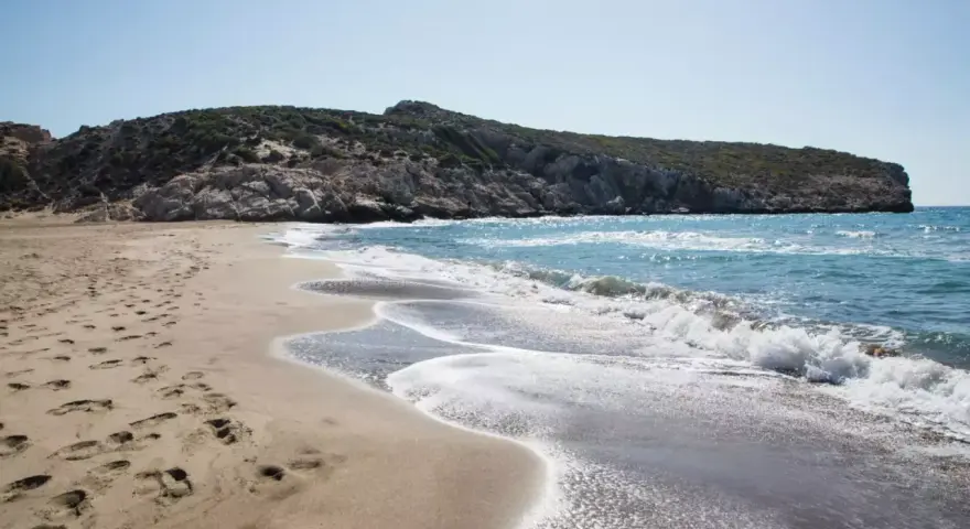 Piękne turcja plaże z piaszczystym brzegiem i skalistym wzgórzem w tle. Fale delikatnie rozbijają się o brzeg.
