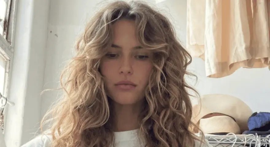 Chica con pelo rizado y flequillo desfilado, inspirador para tipos de flequillo para pelo rizado.