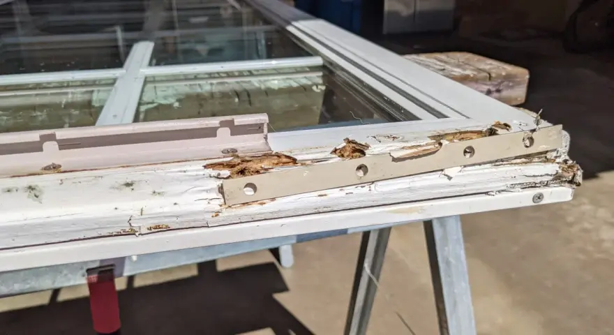 Damaged wood window frame, showing rot and peeling paint, indicating a need for wood window repair.