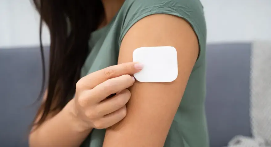 Kobieta przykleja plaster antykoncepcyjny. Przed użyciem warto zapoznać się z przeciwwskazaniami.