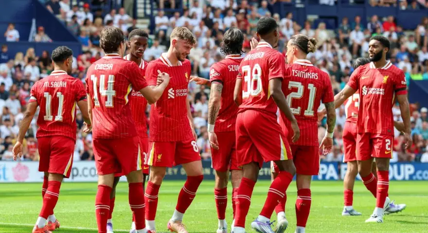 Piłkarze Liverpoolu, mistrzowie Anglii, świętują na boisku. Widać numery 11, 14, 8, 38, 21 i 2.
