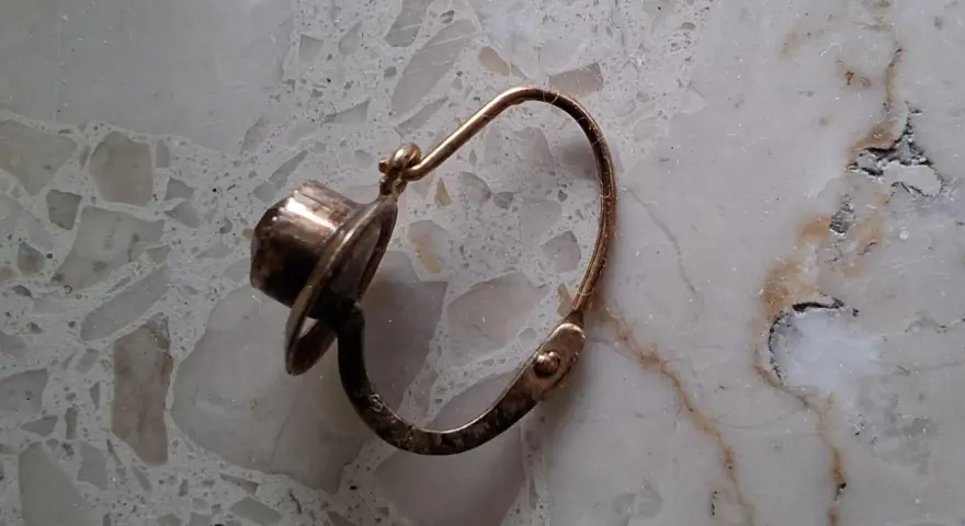 Orecchino d'oro con pietra scura, un po' consumato dal tempo, segno che l'oro si ossida.