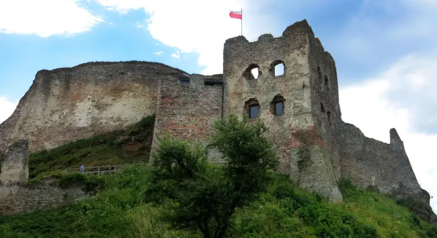 Zamek Czorsztyn, majestatyczne ruiny na wzgórzu, dumnie prezentuje polską flagę na tle błękitnego nieba.
