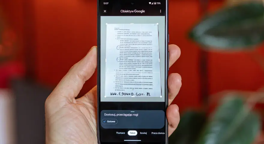 Telefon skanuje dokument, pokazując, jak zeskanować zdjęcie telefonem. Widoczny jest interfejs aplikacji Obiektyw Google.