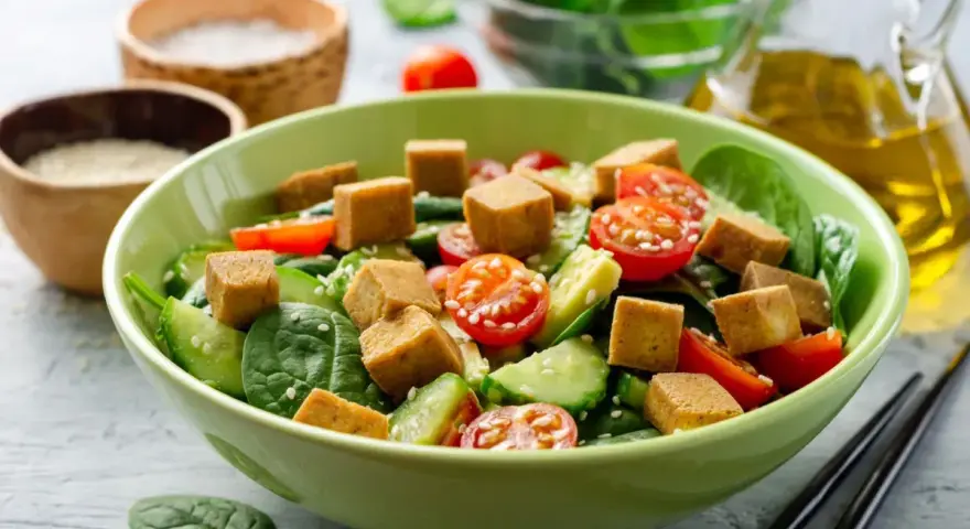 Kolorowa sałatka ze szpinakiem, pomidorkami, ogórkiem i kostkami złocistego tofu. Idealna inspiracja na zdrowe tofu przepisy.