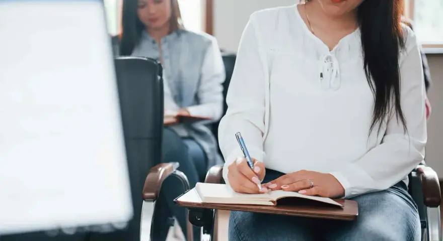 Estudiantes toman notas en clase. Se registran los gastos de formación en la cuenta contable.