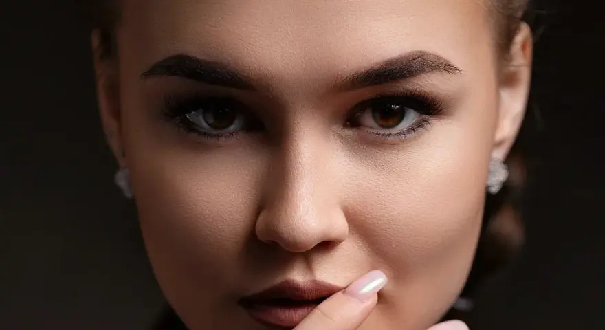 Un gros plan sur le visage d'une femme, ses sourcils parfaitement dessinés après une séance d'épilation.