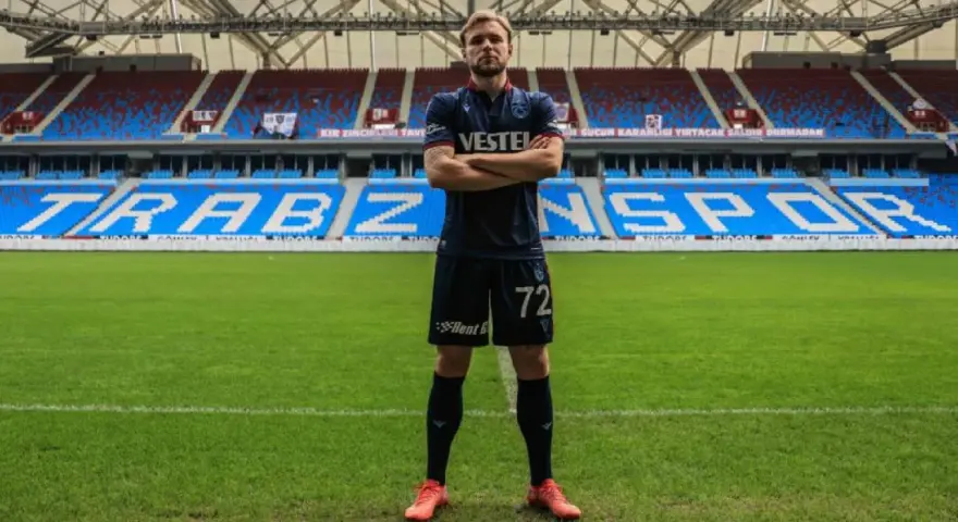 Piłkarz Tymek Puchacz w koszulce Trabzonspor z numerem 72, stoi na murawie stadionu.