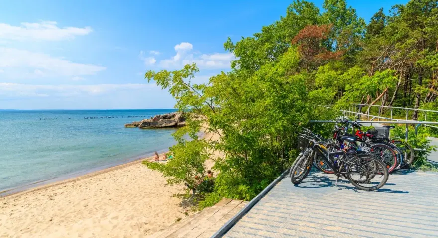 Rowerzyści odpoczywają na plaży, a ich rowery czekają na dalszą podróż po malowniczych pomorskich trasach rowerowych.