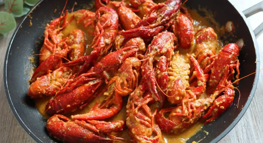 Un delicioso cangrejo de río en una sartén, bañado en una cremosa salsa. ¡Un manjar listo para disfrutar!