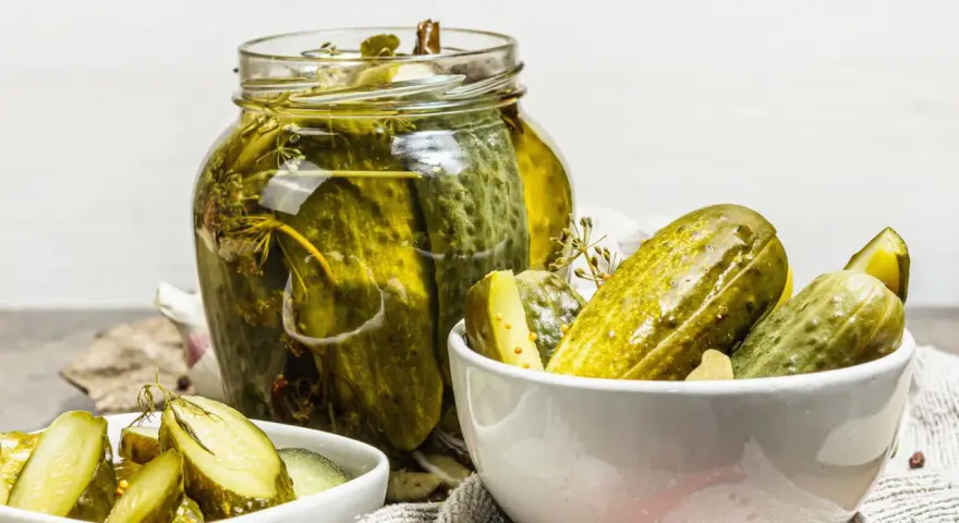 Vaso di cetriolini in agrodolce, con alcuni in una ciotola. Perfetti per un antipasto croccante e saporito.