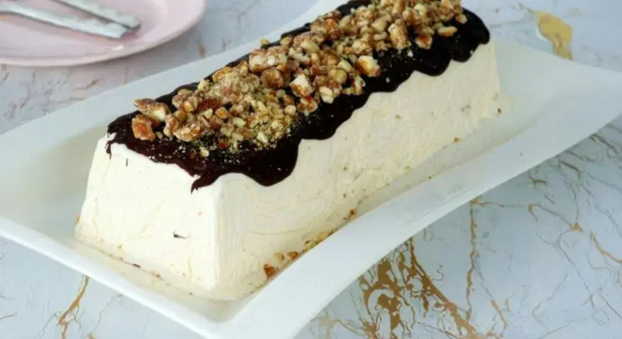 Un delizioso parfait di mandorle, ricoperto di cioccolato fuso e granella croccante, pronto per essere gustato.