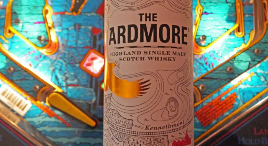 Flasche "The Ardmore" Highland Single Malt Scotch Whisky steht vor einem bunten Flipperautomaten. Ein spannender Ardmore Whisky Test!