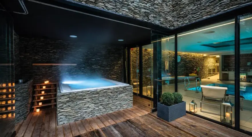 Relaks w nowoczesnym spa na Dolnym Śląsku: jacuzzi z kamienną obudową, basen i nastrojowe oświetlenie.