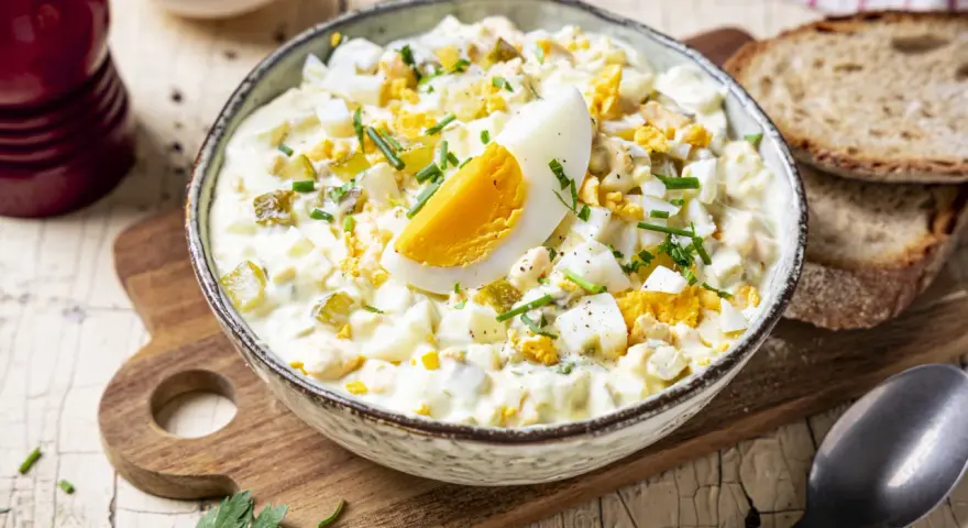 Cremiger Eiersalat mit Gurken und Kräutern, garniert mit einem Ei-Viertel. Ein köstliches eiersalat rezept für jede Gelegenheit.