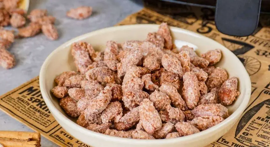Schüssel mit gerösteten Mandeln, die mit Zimt und Zucker bestreut sind. Ein gesunder Snack, der gut schmeckt.