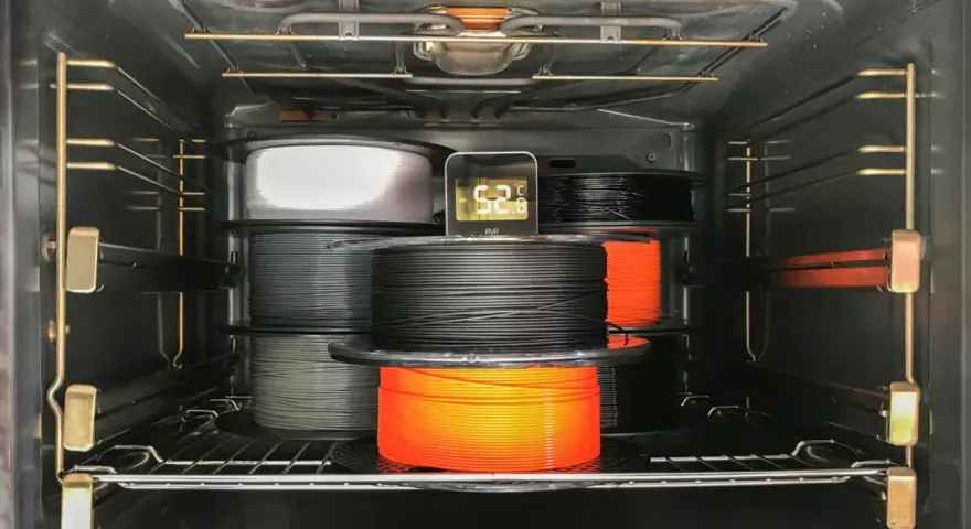 Szpule filamentu do druku 3D, materiał higroskopijny, suszone w piekarniku. Termometr pokazuje 52.8°C.