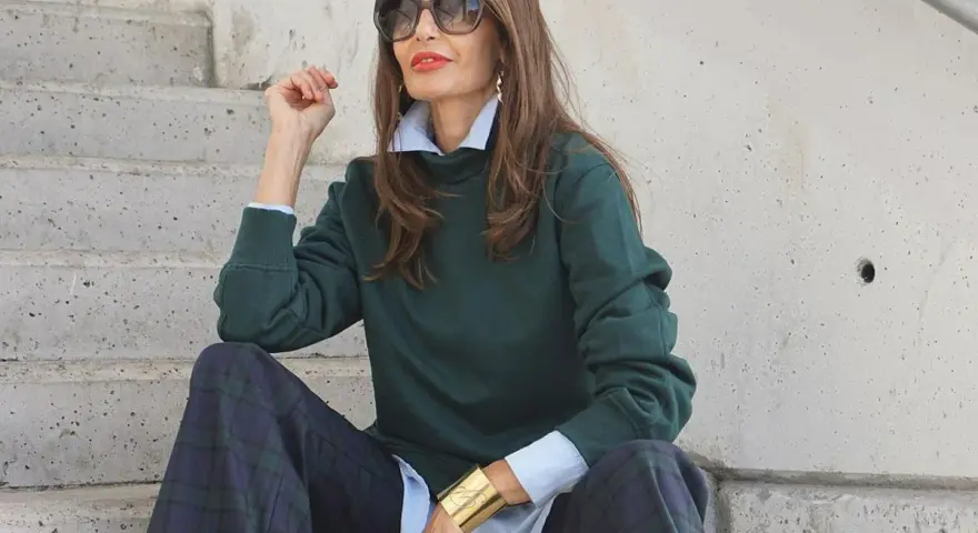 Elegancka kobieta po 50-tce w zielonej bluzie i kratkowych spodniach. Stylowe moda po 50-tce stylizacje.