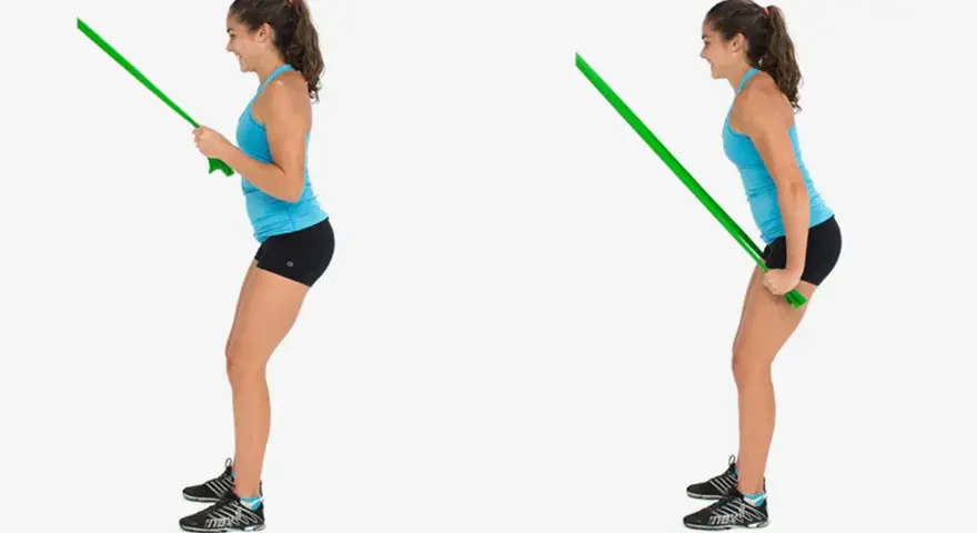 Kvinnlig atlet utför triceps pushdown med ett grönt träningsband.