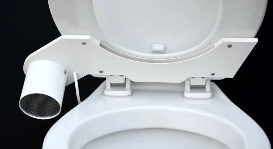 En vit toalett med en innovativ SOG-lösning. En liten cylinder med galler sitter monterad på sidan av sitsen.