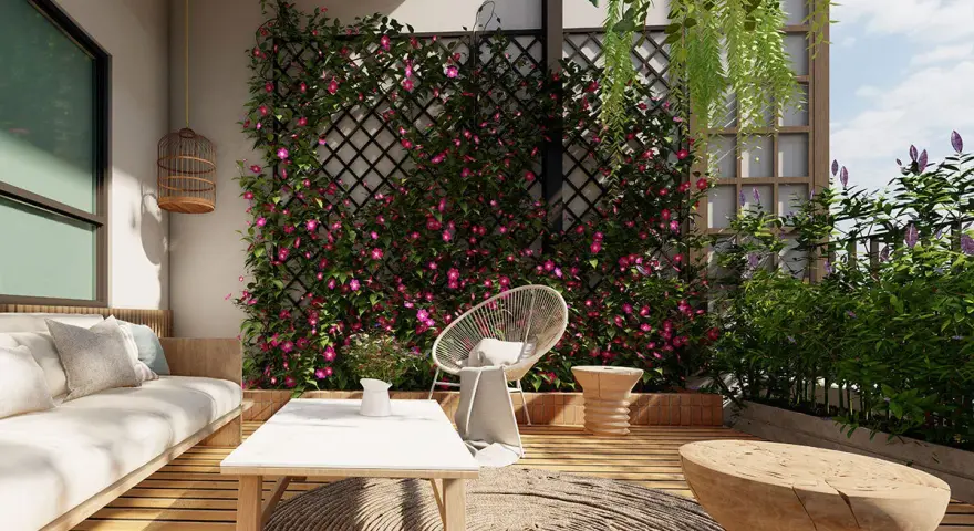 Un terrazzo fiorito con rampicanti rosa su una grata, un divano bianco, tavolino e seduta in rattan. Un'idea per come abbellire una parete con la natura.