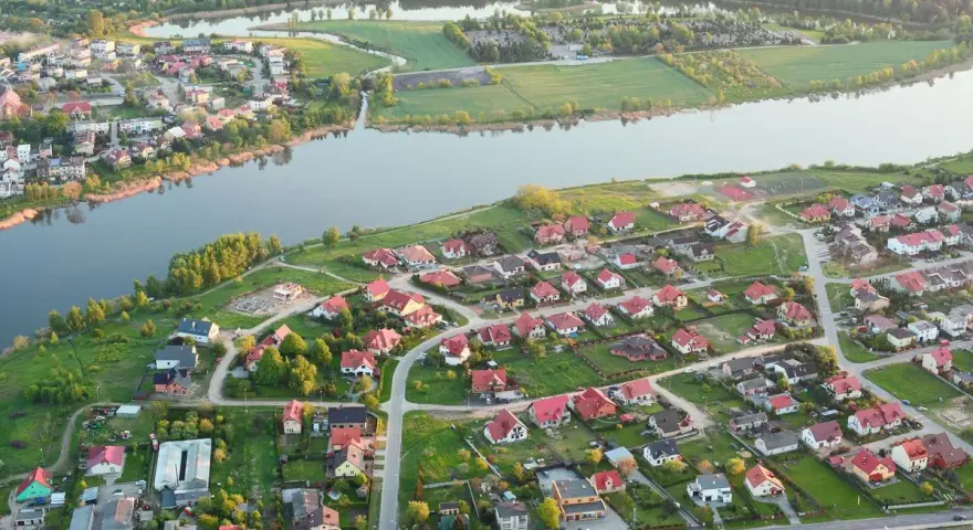 Widok z lotu ptaka na malownicze jezioro Pniewy otoczone zielenią i zabudowaniami.