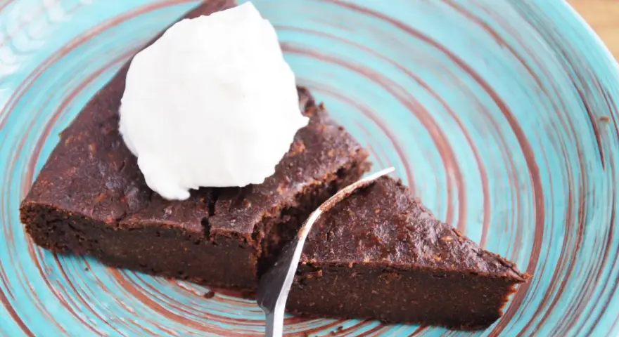 Pyszne keto brownie z cukinii, podane z bitą śmietaną na turkusowym talerzu. Idealne na deser bez wyrzutów sumienia.