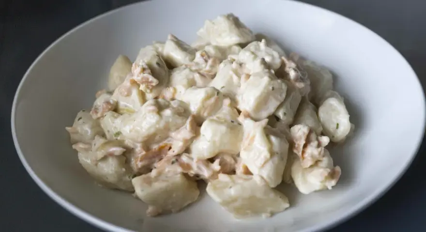 Gnocchi ziemniaczane kontra gnocchi z ricotty w kremowym sosie z łososiem. Pyszne danie w białej misce.