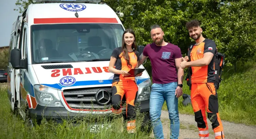 Trzech ratowników medycznych stoi obok karetki. Zastanawiasz się, ile godzin pracuje ratownik medyczny?