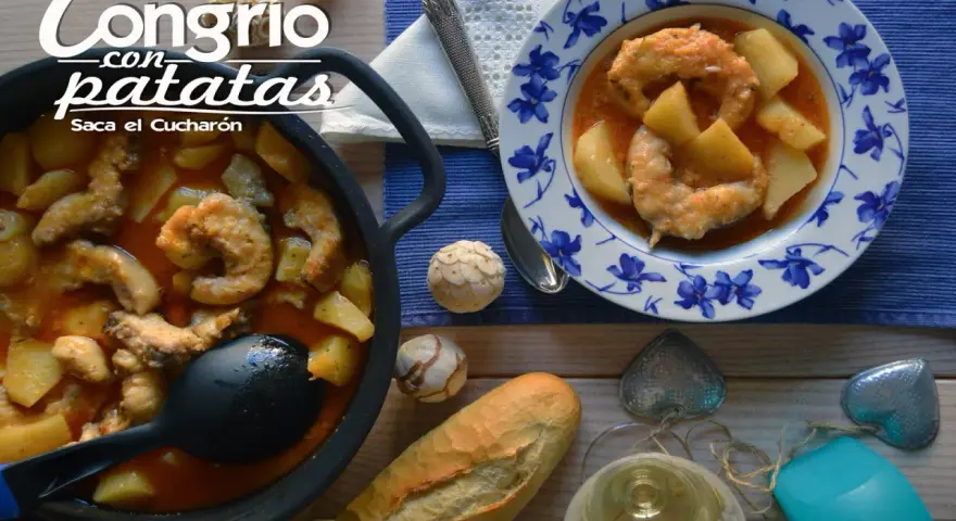 Congrio con patatas, un plato reconfortante servido en cazuela y plato decorado. Acompañado de pan y vino blanco.
