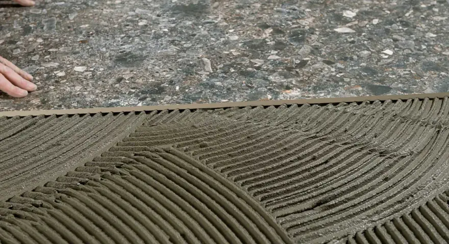 Pose de mortier pour un double encollage de carrelage. Les mains d'un carreleur préparent la surface.