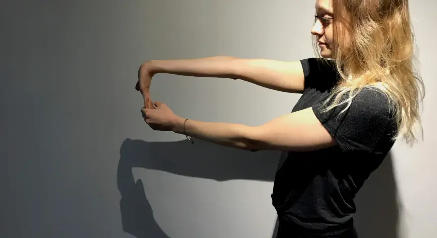 Jeune femme faisant un étirement du poignet, geste clé pour la rééducation de l'épitrochléite et réduire le temps de guérison.