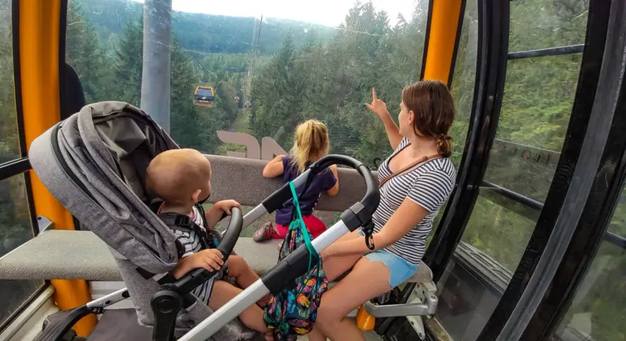 Rodzina w kolejce gondolowej w Górach Izerskich, Świeradów-Zdrój. Dzieci zachwycone widokiem lasu i innych wagoników.